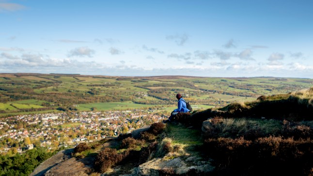 Person sits on top of the rocks on Ilkley Moor, West Yorkshire.