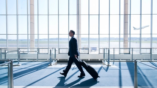 Caucasian businessman pulling luggage in airport