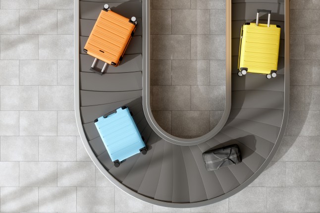 Four suitcases moving on an airport conveyor belt.