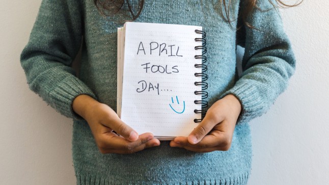 Little girl holding a notebook in which puts Aprils Fool Day