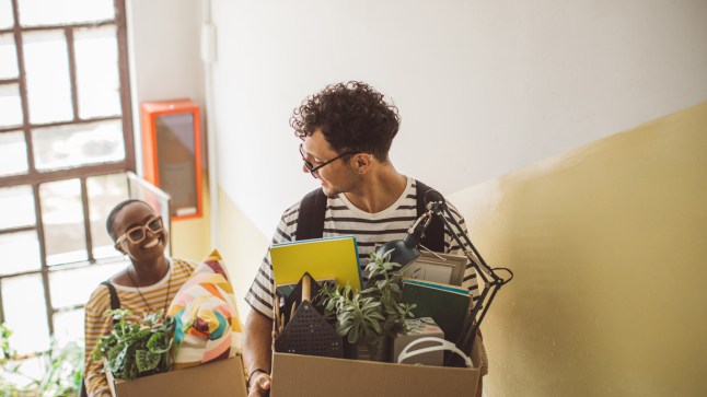 Young people move boxes full of their belongings into a new house.