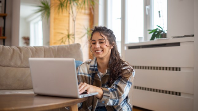Woman sitting on the floor typing on a laptop.