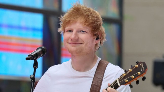 Ed Sheeran playing guitar and smiling at a crowd