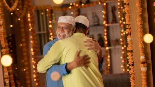 Father and son in skull caps embracing during Eid-Ul-Fitr