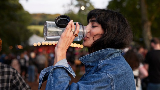 Woman drinking water from a bottle at a festival.