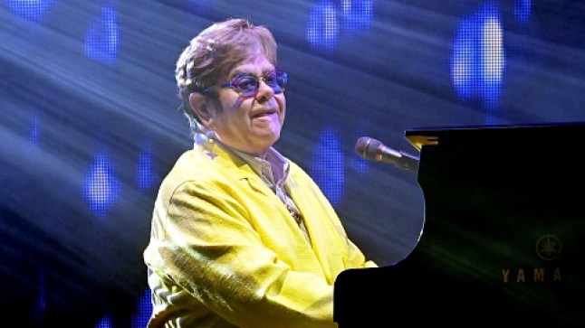Elton John in yellow suit playing piano