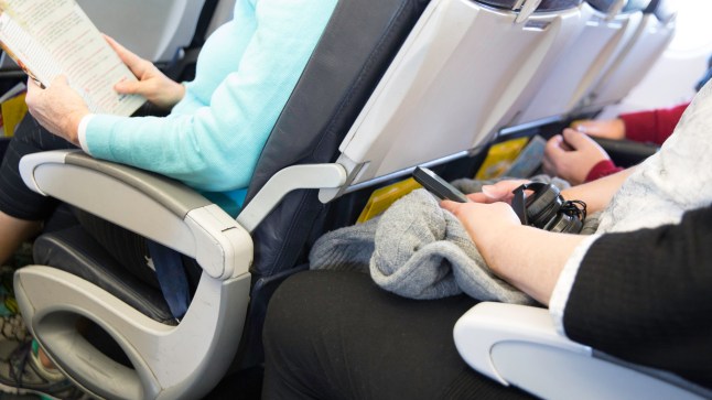 Passengers seated on an airplane are cramped in their seats