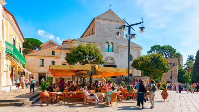 People sitting outside in the sunshine at street café in the central square in Ravello on the Amalfi Coast.