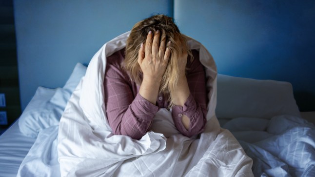 Woman in bed with her head in her hands