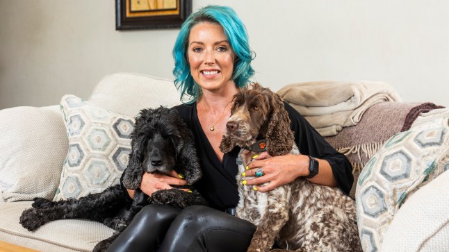 Camilla on the sofa in her £1,800pcm Wiltshire flat, hugging her two dogs
