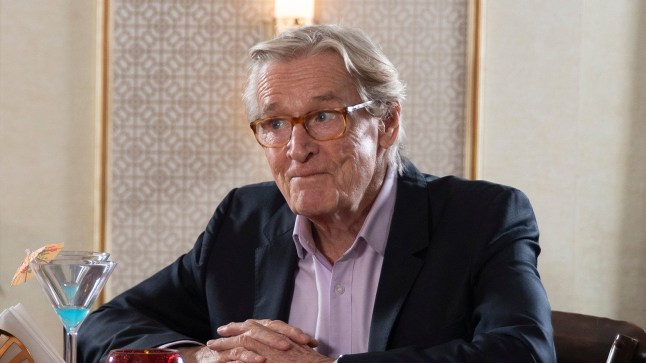 Ken Barlow smiles as he sits at a table in Corrie
