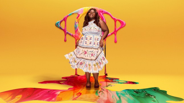 Daze Aghaji posing in a patterned dress in a promotional shot for Big Brother 2024, against a yellow backdrop with a paint-covered BB eye