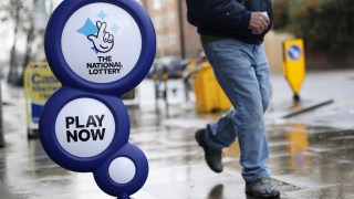 National Lottery sign with man walking past.