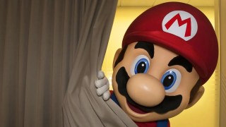 Man in a Super Mario costume peeking from behind a curtain