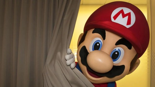 Man in a Super Mario costume peeking from behind a curtain
