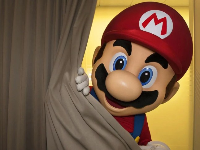 Man in a Super Mario costume peeking from behind a curtain
