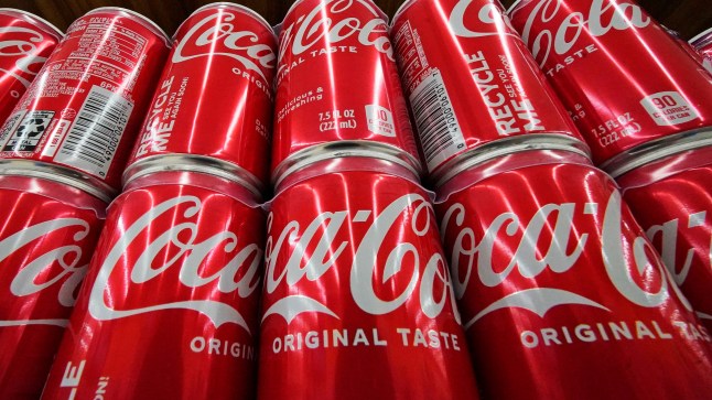 FILE - Cans of Coca-Cola are on display at a grocery market in Uniontown, Pa, April 24, 2022. (AP Photo/Gene J. Puskar, File)