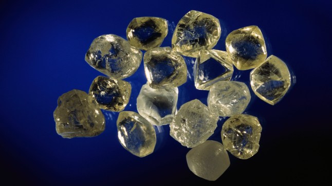 Several diamonds placed on a dark blue surface.