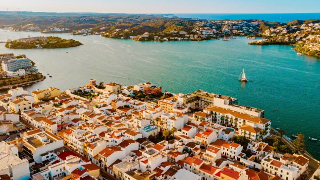 An aerial view of Es Castell on the Menorca coast, looking over orange-roofed buildings and the sea.