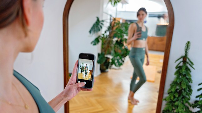 A young woman takes a selfie in the mirror in sportswear while preparing for exercise