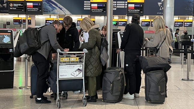 Passengers queue at a check-in desk at Heathrow Terminal 2 in London. Flights resumed at the west London airport on Friday evening and restrictions on overnight flights were temporarily lifted following hours of closure, after a blaze knocked out an electricity substation in Hayes late on Thursday evening.