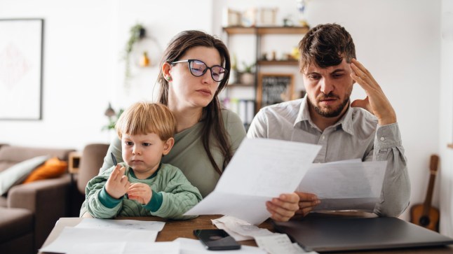 Young family of three with a toddler managing their budget,paying bills and taxes online and calculating monthly expenses at home.Inflation concept.