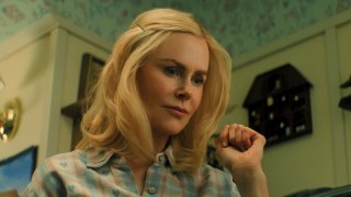 Nicole Kidman as Nancy Vandergroot holds up her fist near her face as she stands in a vintage-style kitchen in the film Holland