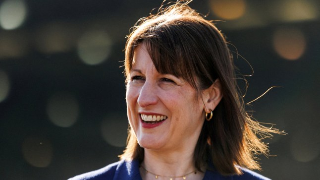 Rachel Reeves, a woman with brown hair, is seen looking away from the camera and smiling as the sun shines on her