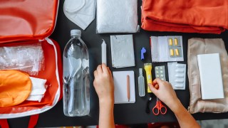 Close-up of women's hands putting a survival kit together.